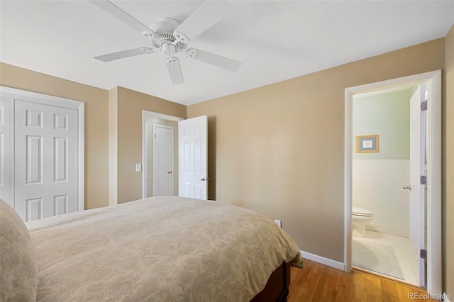 bedroom featuring ensuite bathroom, a ceiling fan, wood finished floors, a closet, and baseboards