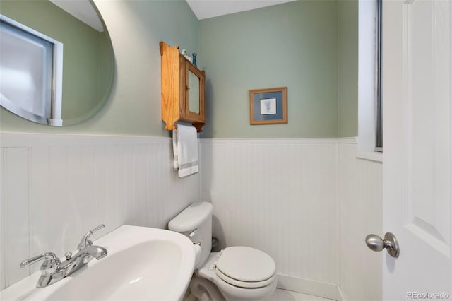 bathroom with a sink, toilet, and wainscoting