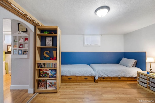 bedroom featuring wood finished floors, baseboards, and a textured ceiling