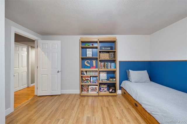 bedroom featuring wood finished floors, baseboards, and a textured ceiling