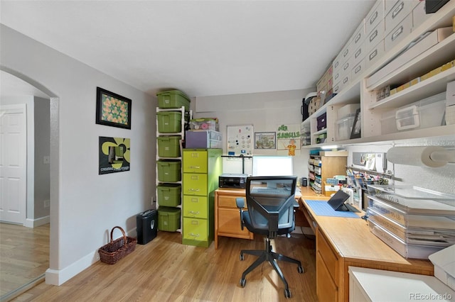 office with baseboards, arched walkways, and light wood-style flooring