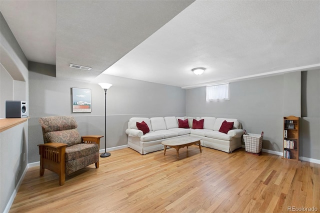 living area with visible vents, baseboards, and wood finished floors