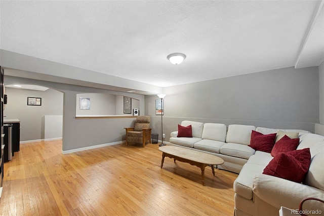 living room with baseboards, light wood-type flooring, and a textured ceiling