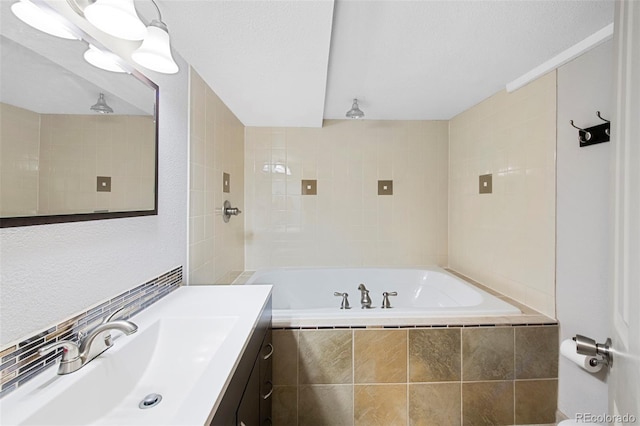 bathroom with vanity, a textured ceiling, a relaxing tiled tub, and tiled shower