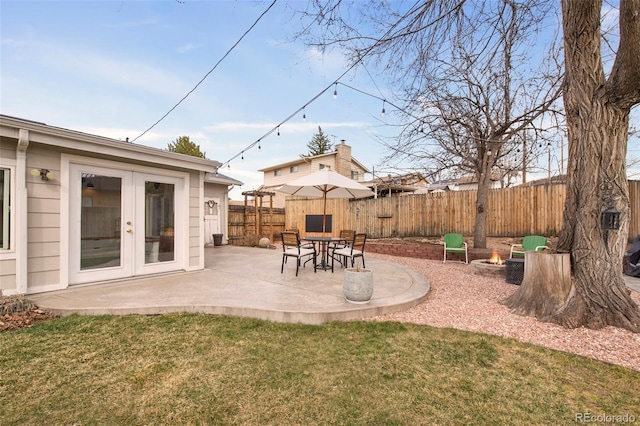 view of yard with a patio area, french doors, a fenced backyard, and a fire pit