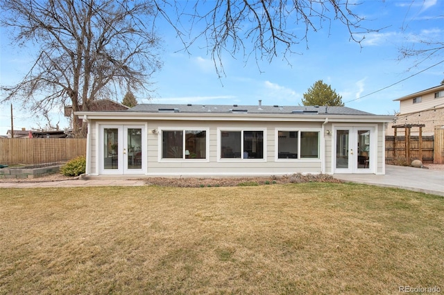 back of property with french doors, a lawn, a patio area, and fence