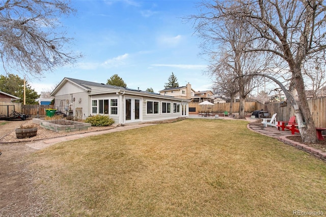 rear view of house with a lawn, a fenced backyard, french doors, a garden, and a patio area