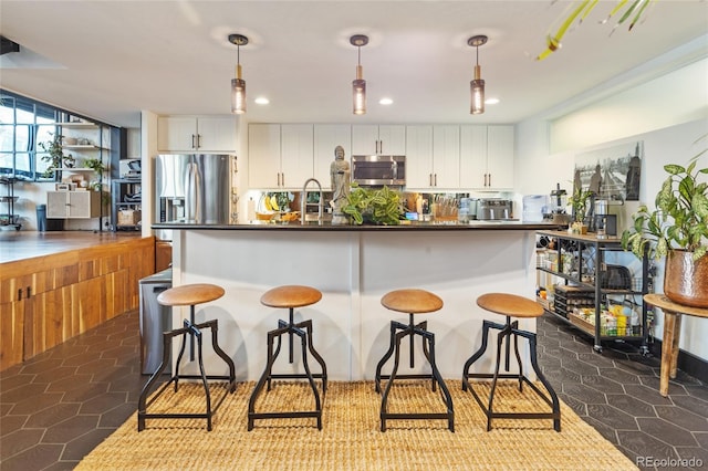 1203 24th St, Denver, CO 80205 - kitchen with appliances with stainless steel finishes, white cabinets, dark countertops, a breakfast bar, and recessed lighting