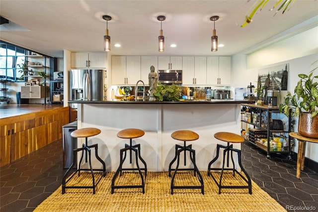 1203 24th St, Denver, CO 80205 - kitchen with stainless steel appliances, dark countertops, white cabinets, a kitchen breakfast bar, and recessed lighting