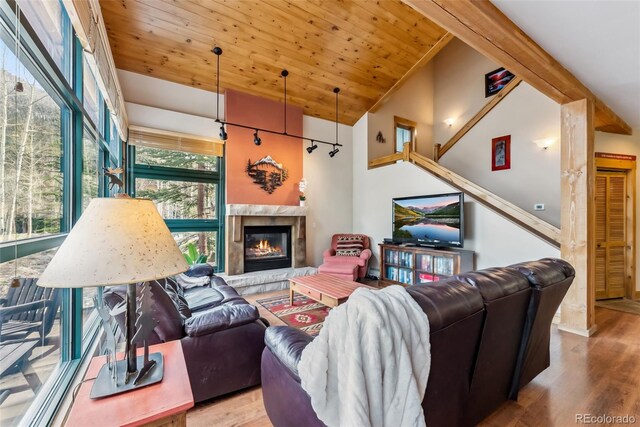 living area featuring wood finished floors, a premium fireplace, vaulted ceiling, and wood ceiling
