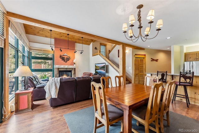 dining room with light wood-style floors, recessed lighting, a chandelier, a high end fireplace, and stairway