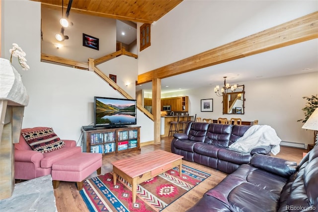 living area featuring wood finished floors, a baseboard heating unit, a chandelier, wood ceiling, and a high ceiling