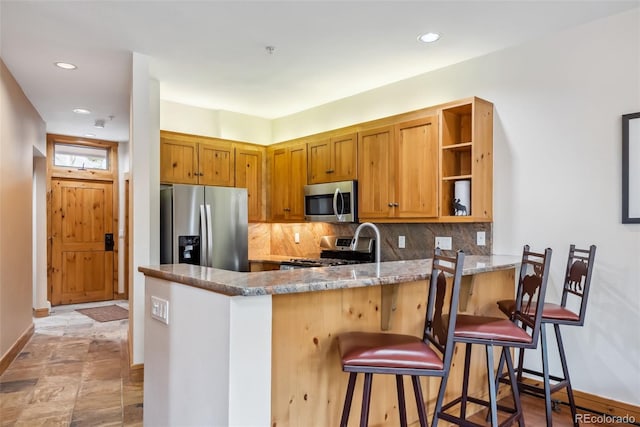 kitchen with appliances with stainless steel finishes, open shelves, decorative backsplash, a peninsula, and baseboards