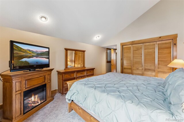 bedroom featuring light colored carpet, a glass covered fireplace, vaulted ceiling, and recessed lighting