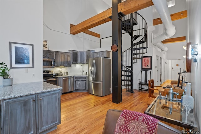 kitchen featuring sink, beam ceiling, stainless steel appliances, and a high ceiling