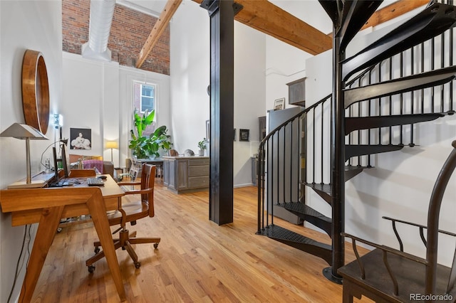 interior space with beamed ceiling, a towering ceiling, and light hardwood / wood-style floors