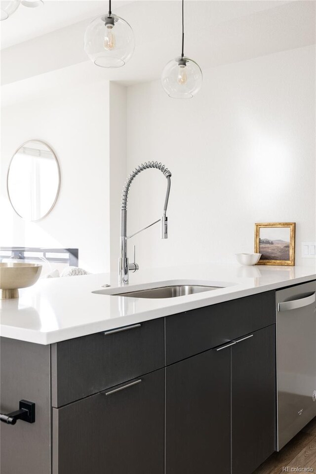 kitchen with pendant lighting, stainless steel dishwasher, dark hardwood / wood-style flooring, and sink