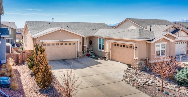 5279 Mount Cutler Ct, Colorado Springs, CO 80924 - view of front of house featuring an attached garage, driveway, stone siding, and stucco siding