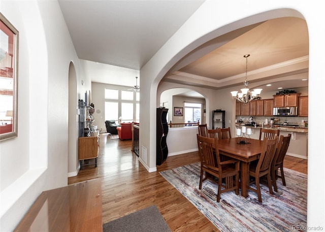 5279 Mount Cutler Ct, Colorado Springs, CO 80924 - dining room with crown molding, wood finished floors, baseboards, a tray ceiling, and arched walkways