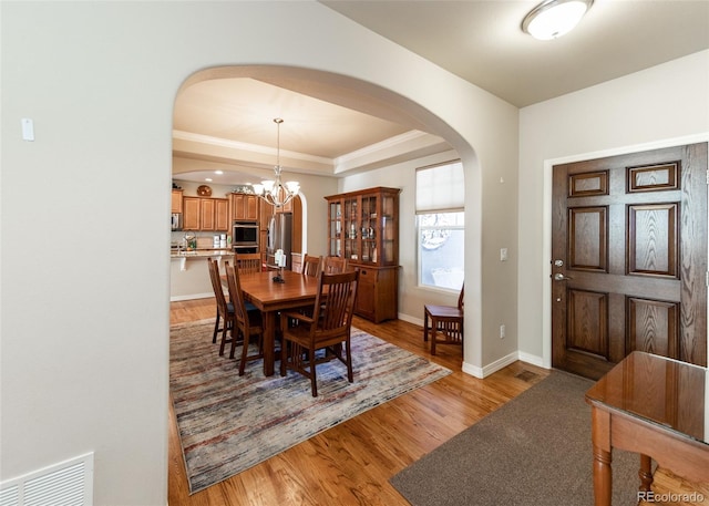 5279 Mount Cutler Ct, Colorado Springs, CO 80924 - dining area featuring visible vents, an inviting chandelier, baseboards, arched walkways, and light wood finished floors