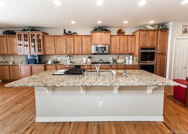 5279 Mount Cutler Ct, Colorado Springs, CO 80924 - kitchen with a large island with sink, appliances with stainless steel finishes, a breakfast bar area, and light stone countertops