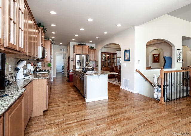 5279 Mount Cutler Ct, Colorado Springs, CO 80924 - kitchen featuring a kitchen island, visible vents, light stone countertops, light wood-style floors, and stainless steel appliances