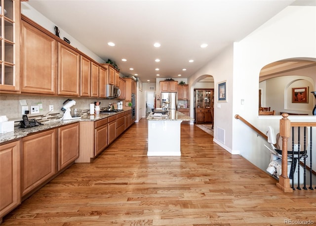 5279 Mount Cutler Ct, Colorado Springs, CO 80924 - kitchen featuring recessed lighting, light stone counters, arched walkways, light wood-style flooring, and appliances with stainless steel finishes