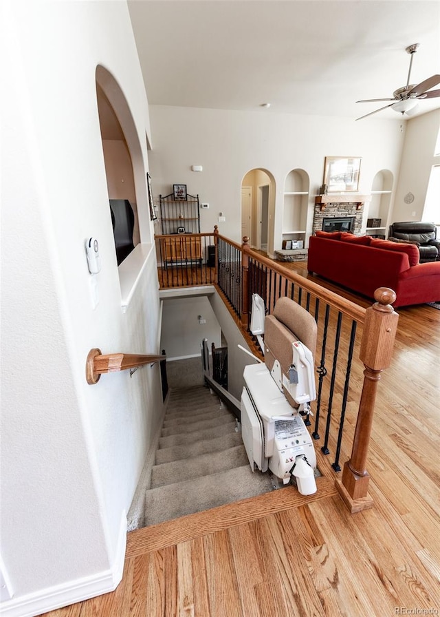5279 Mount Cutler Ct, Colorado Springs, CO 80924 - stairs featuring arched walkways, ceiling fan, a fireplace, and wood finished floors