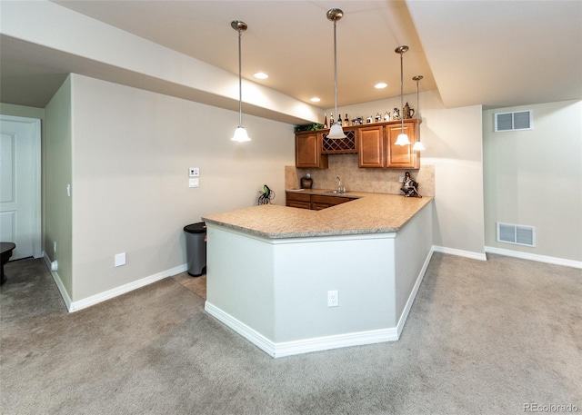 5279 Mount Cutler Ct, Colorado Springs, CO 80924 - kitchen featuring visible vents, brown cabinetry, a peninsula, light carpet, and tasteful backsplash
