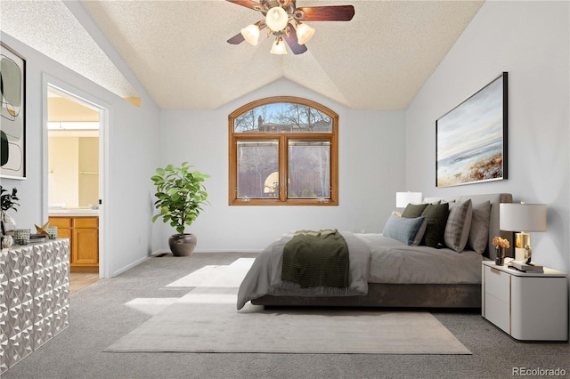 bedroom featuring light colored carpet, vaulted ceiling, ensuite bathroom, a textured ceiling, and a ceiling fan