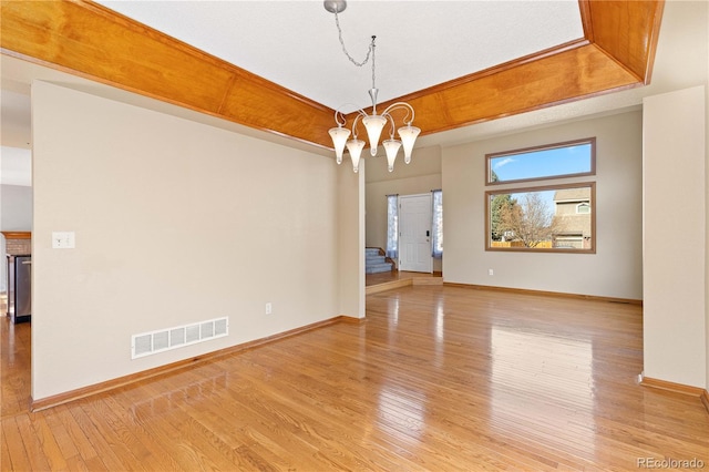 unfurnished room with a notable chandelier, visible vents, light wood-style flooring, and baseboards