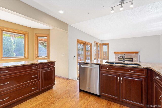 kitchen featuring a sink, stainless steel dishwasher, light wood finished floors, baseboards, and light stone countertops