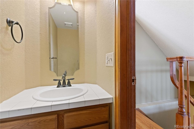 bathroom featuring visible vents, vanity, and a textured wall