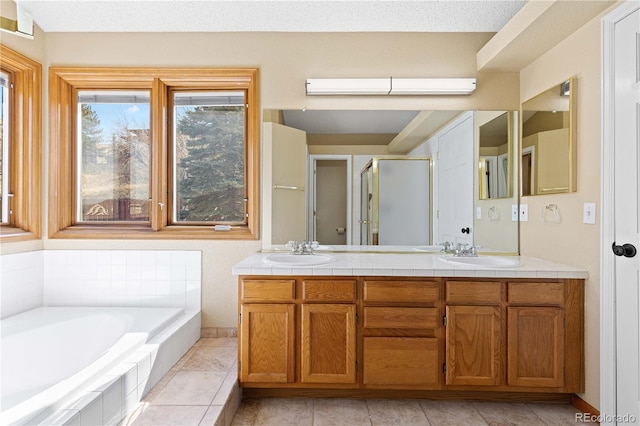 bathroom featuring double vanity, a garden tub, a shower stall, and a sink