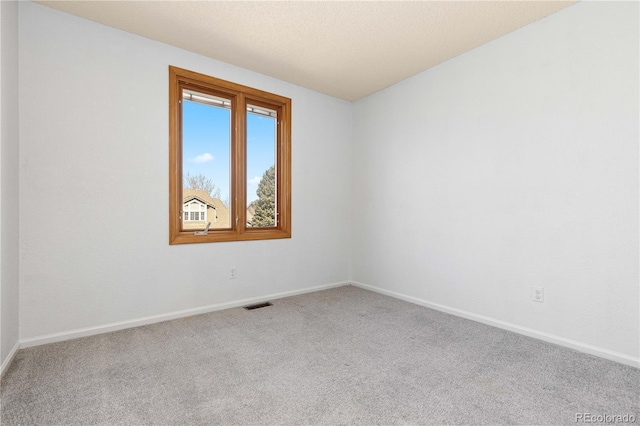 carpeted spare room with baseboards and visible vents