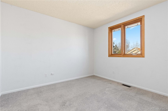 carpeted spare room featuring visible vents, a textured ceiling, and baseboards