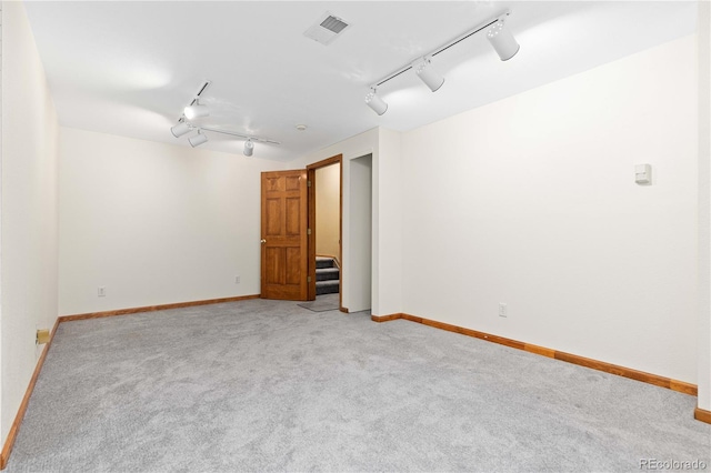 carpeted spare room featuring track lighting, baseboards, and visible vents