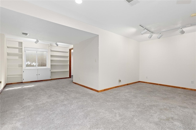 carpeted empty room featuring visible vents, baseboards, and rail lighting