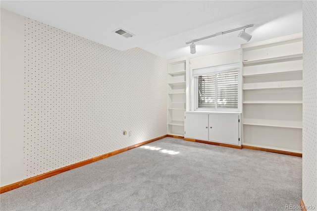 spare room featuring visible vents, carpet floors, rail lighting, wallpapered walls, and baseboards