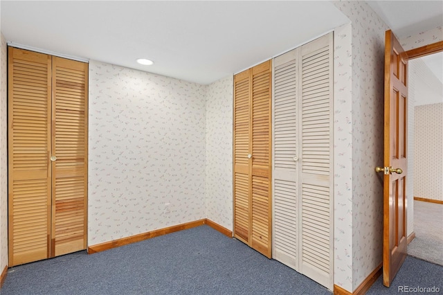 unfurnished bedroom with wallpapered walls, two closets, baseboards, carpet, and recessed lighting