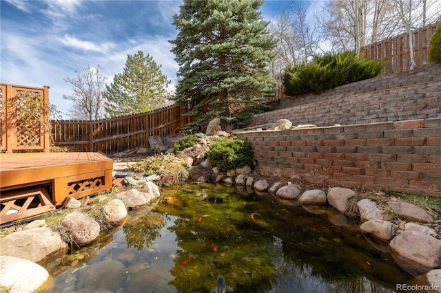 view of yard featuring fence and a small pond