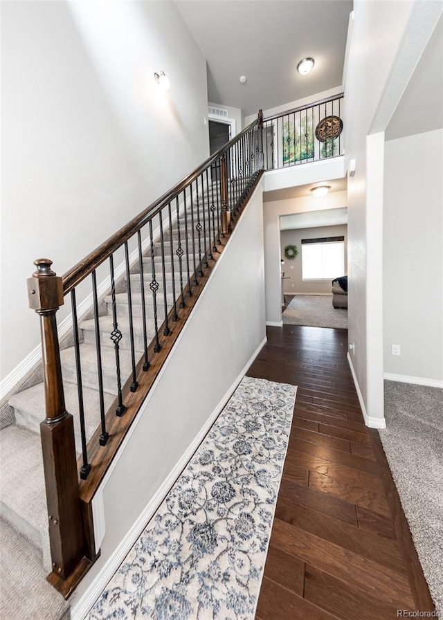 9835 Rubicon Dr, Colorado Springs, CO 80925 - staircase featuring hardwood / wood-style flooring, baseboards, and a towering ceiling