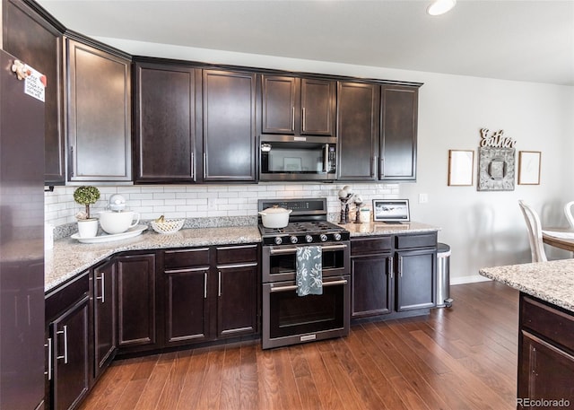 9835 Rubicon Dr, Colorado Springs, CO 80925 - kitchen featuring appliances with stainless steel finishes, dark wood-style floors, light stone countertops, dark brown cabinetry, and backsplash