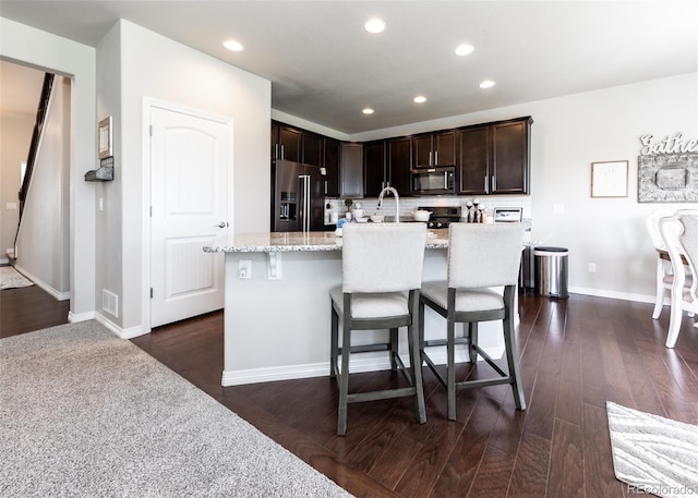 9835 Rubicon Dr, Colorado Springs, CO 80925 - kitchen with refrigerator with ice dispenser, black microwave, dark brown cabinetry, a kitchen breakfast bar, and recessed lighting