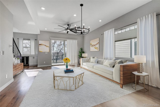 living room with ceiling fan with notable chandelier and dark hardwood / wood-style floors