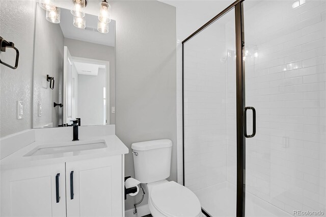 bathroom featuring a shower with door, vanity, and toilet