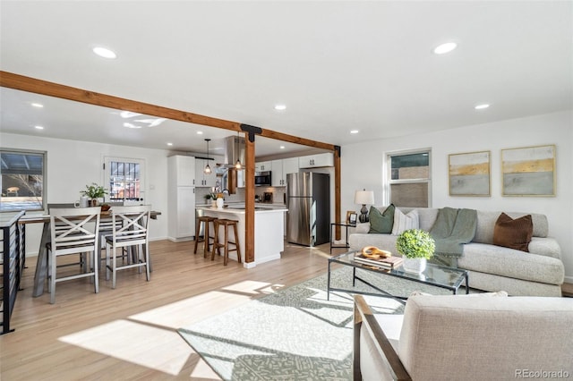 living room with beamed ceiling, sink, and light hardwood / wood-style flooring