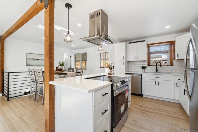 kitchen featuring pendant lighting, stainless steel appliances, island range hood, white cabinets, and a kitchen island