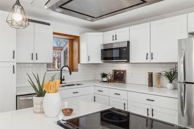 kitchen with decorative light fixtures, white cabinetry, sink, backsplash, and stainless steel appliances