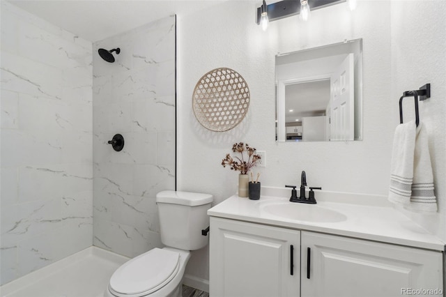 bathroom with vanity, toilet, and a tile shower